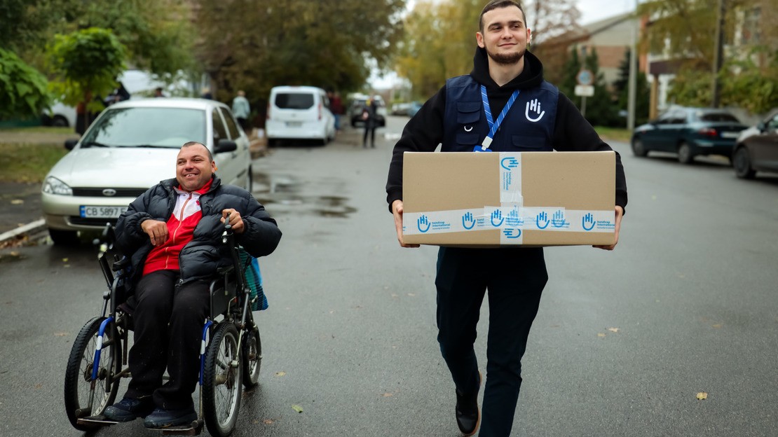 Vadim Loktionov, responsable du projet Besoins de base, aide Pavlo, 39 ans, atteint de paralysie cérébrale, à porter son kit de besoins spéciaux.