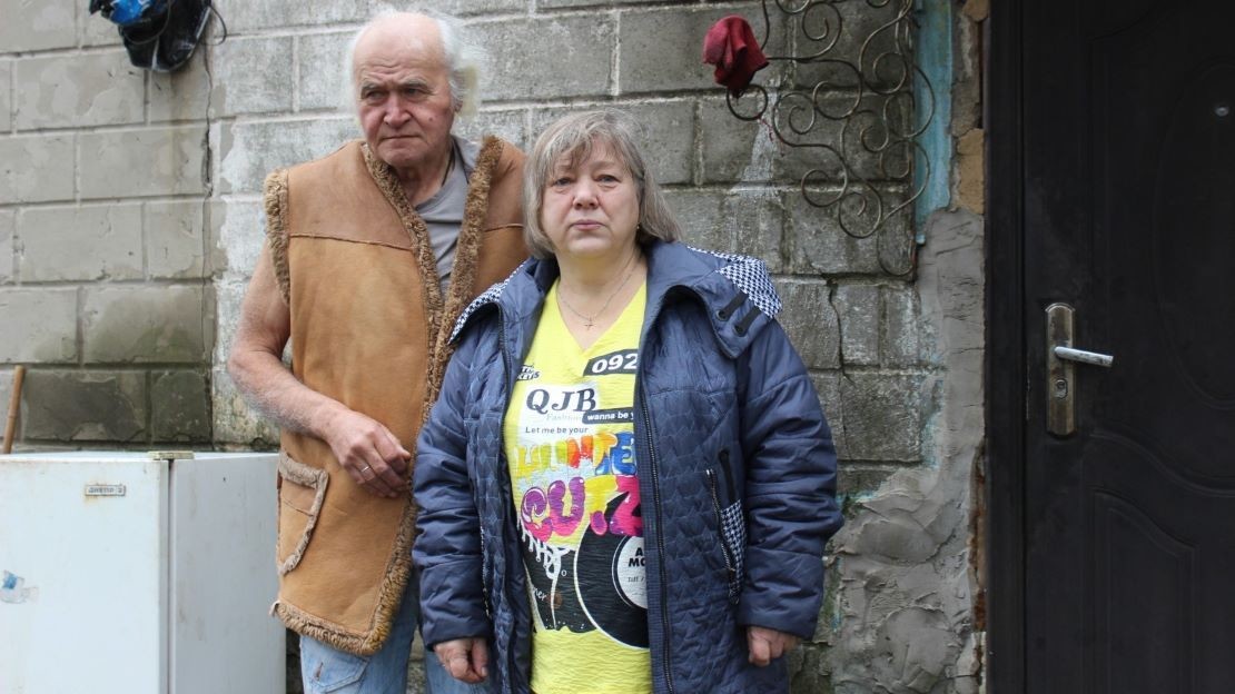 Devant une maison, une femme et un homme se tiennent debout.