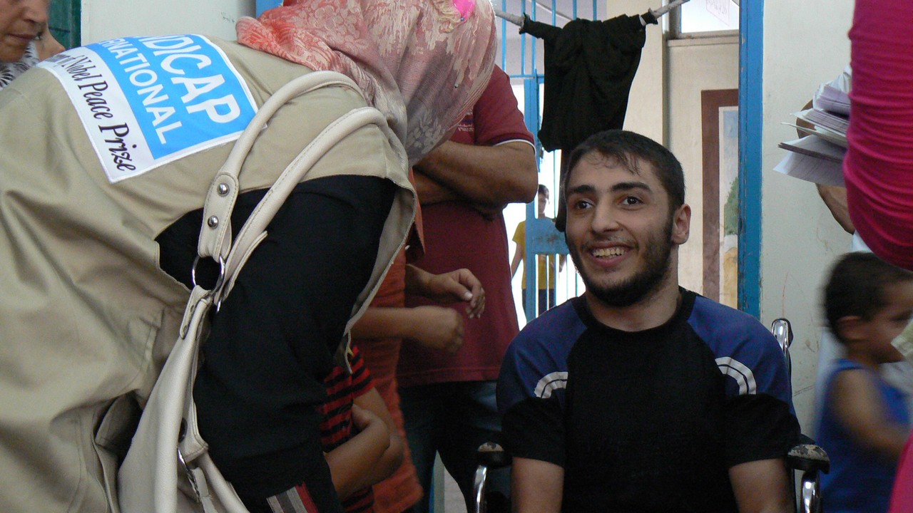 Equipe de Handicap International avec Mohammed, jeune homme handicapé qui a du fuir son quartier avec sa famille.