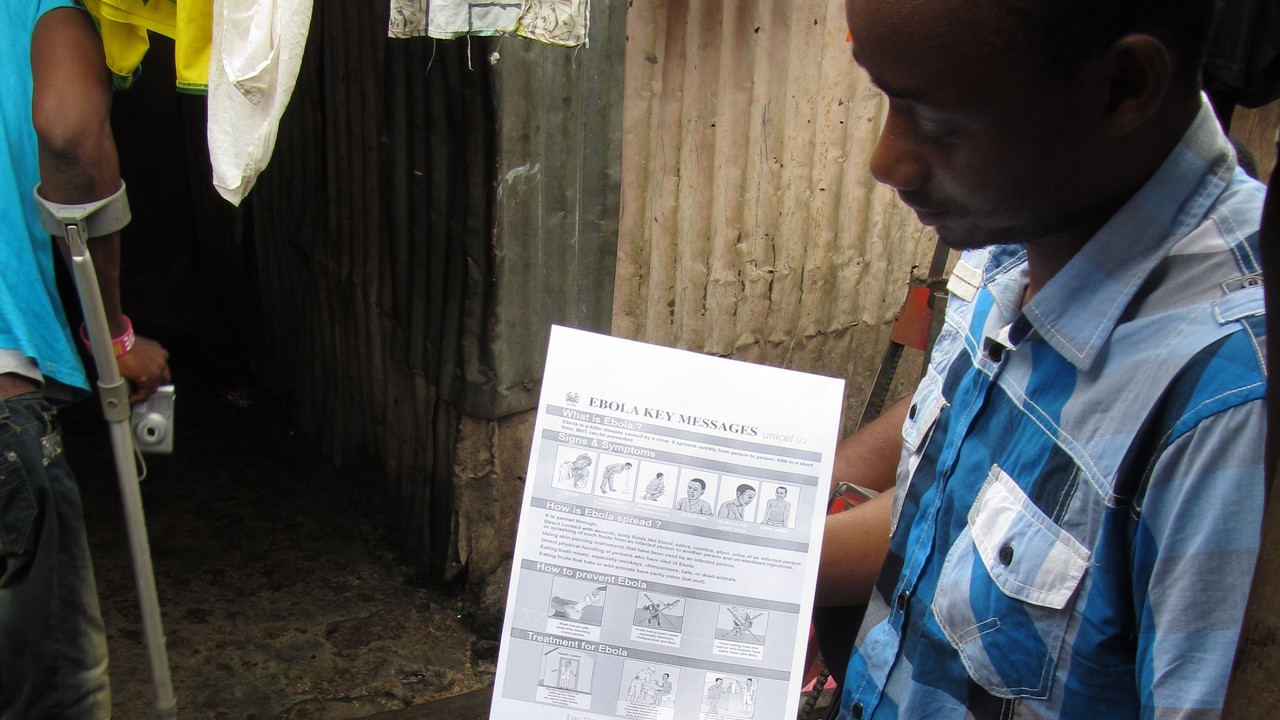 Handicap International : séance de sensibilisation sur le virus ebola auprès d'une communauté dans un bidonville de 90 personnes handicapées et leurs familles.