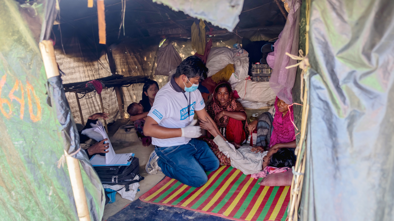 Rubel Sarker, kinésithérapeute de Handicap International, évalue la motricité de Noorayesha dans sa tente au sein d'un camp de réfugiés au Bangladesh