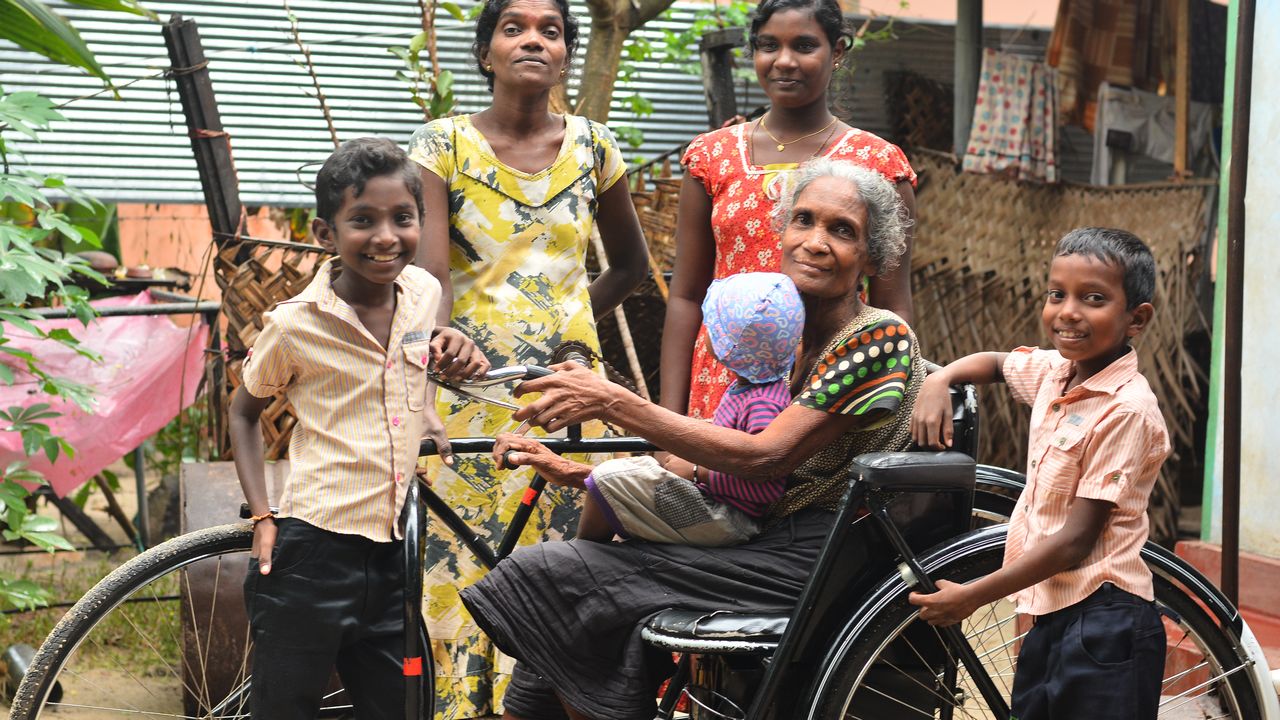 Arumugam, 60 ans, paralysé des jambes vit dans un village du Sri Lanka souvent inondé. Impliquée dans la gestion des risques de catastrophes naturelles, elle a également reçu un tricycle. Sur cette photo, Arumugam est dans son tricycle entourée de ses proches.
