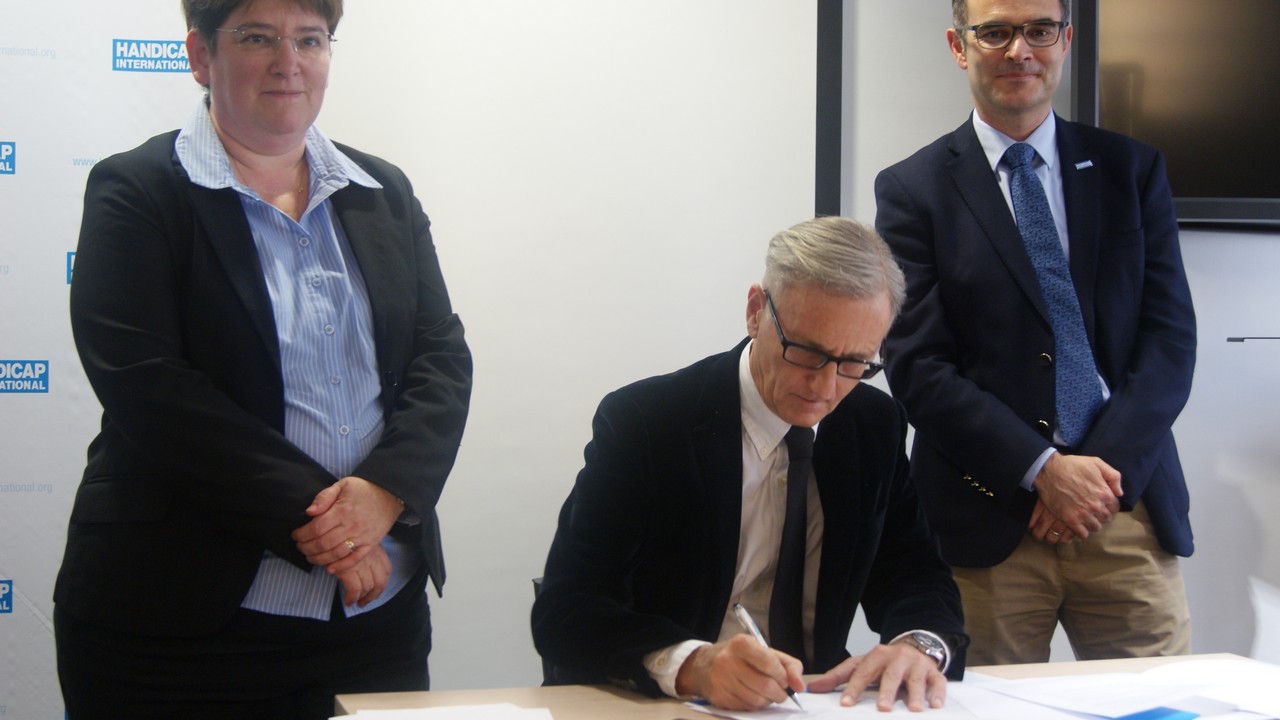 André Vallini, secrétaire d'État chargé du Développement et de la Francophonie, signant la Charte pour l’inclusion des personnes handicapées dans l’action humanitaire au siège de Handicap International