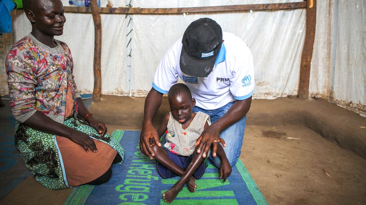 Le kiné de Handicap International montre à Rose les gestes à reproduire avec Samuel pour améliorer son quotidien