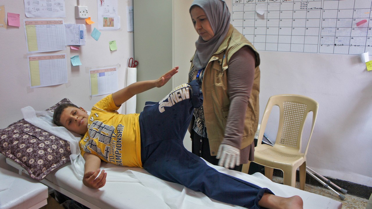 Omar en séance de réadaptation avec Mouna, kinésithérapeute de Handicap International