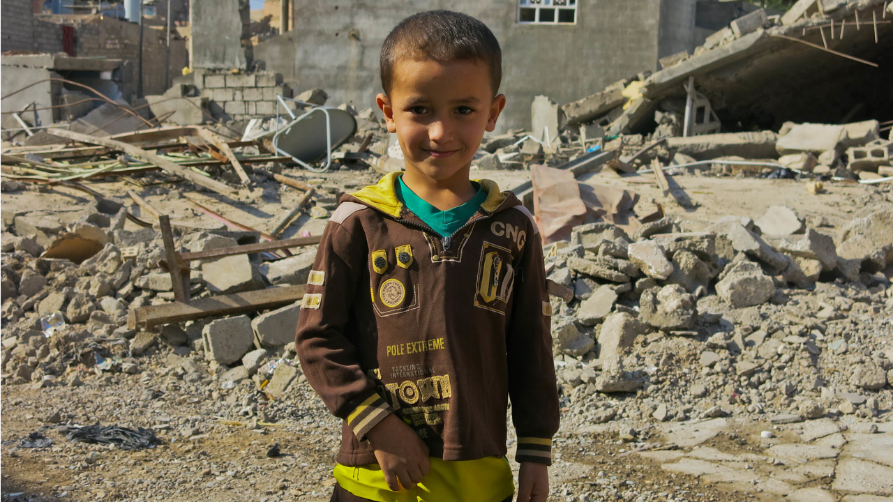 Le fils de Khaled devant la maison de son oncle, dont il ne reste que des ruines