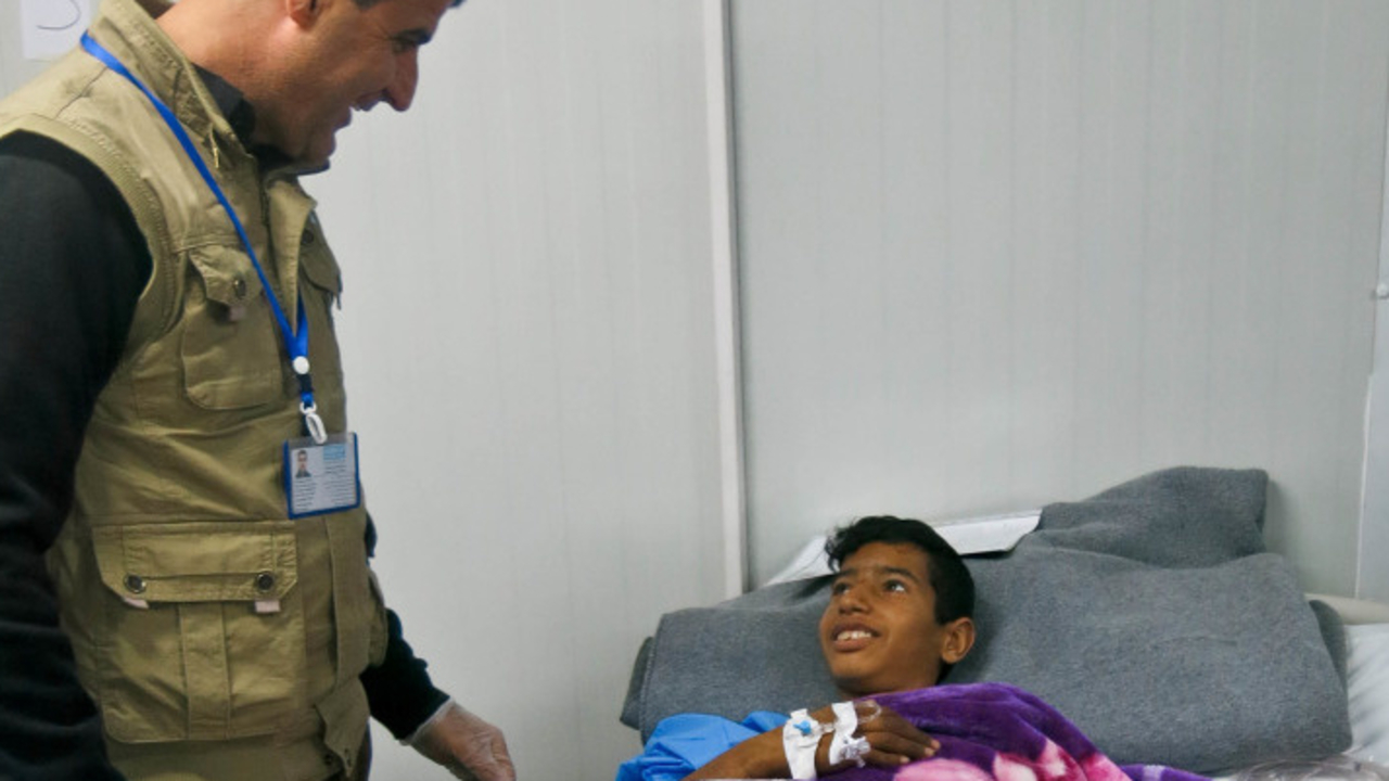 Omar, sur son lit d’hôpital, est accompagné par Handicap International pour sa rééducation