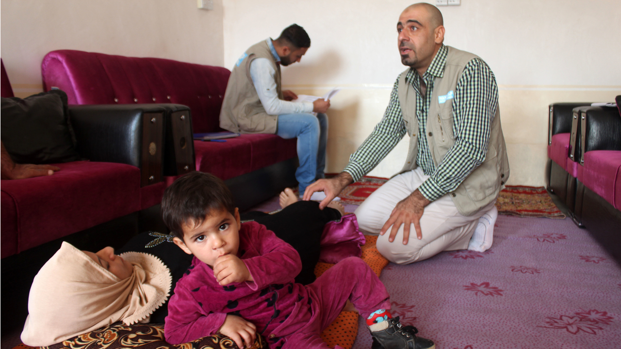 Ola à côté de sa mère, Widad, lors d’une session de kinésithérapie menée par Omar de Handicap International