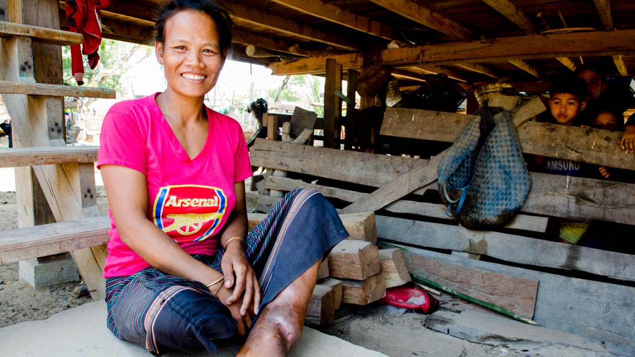 À Tam Luang au Laos, Nang est assise dehors avec sa jambe blessée. Grâce à Handicap International, elle développe une activité qui génère des revenus pour elle et sa famille.