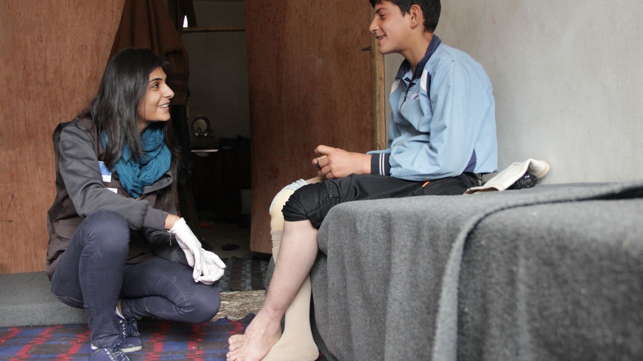 Firas, jeune syrien de 13 ans, amputé d'une partie de la jambe droite s'entretient avec la kinésithérapeute de Handicap International qui lui délivre des soins de kinésithérapie afin qu'il trouve son équilibre avec sa prothèse.
