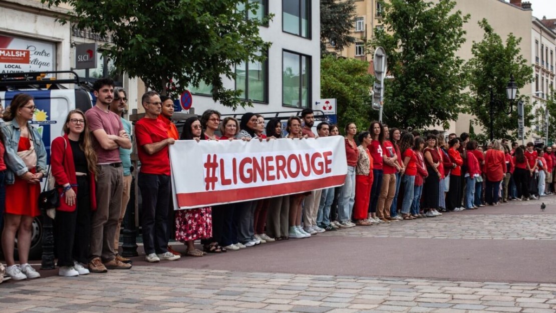 File de personnes habillées de rouge et tenant une banderole #lignerouge.