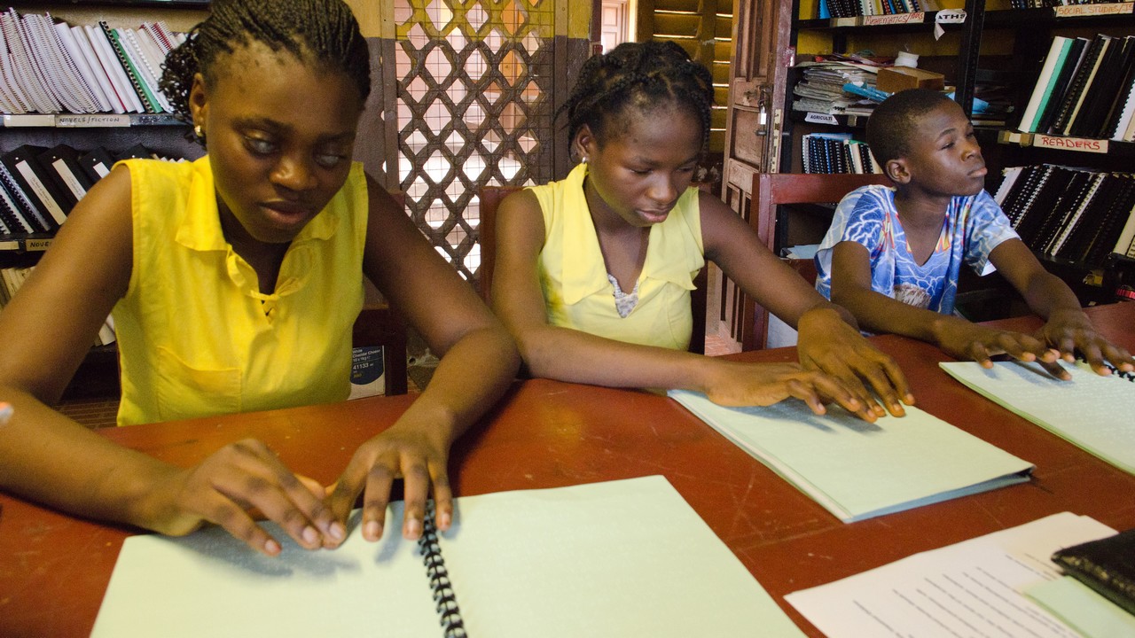 Des étudiants à l'École Maragai Milton pour les aveugles à Freetown, en Sierra Leone, lisent un guide de prévention d'Ébola en braille produit par Handicap International.