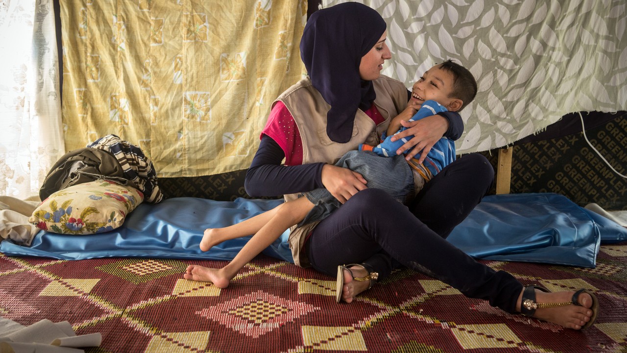 Binan, kinésithérapeute pour Handicap International, prend soin d'Atallah, un jeune réfugié syrien de 9 ans atteint d'infirmité motrice cérébrale, afin d'améliorer son oxygénation, dans un campement à proximité de Tripoli au nord du Liban.