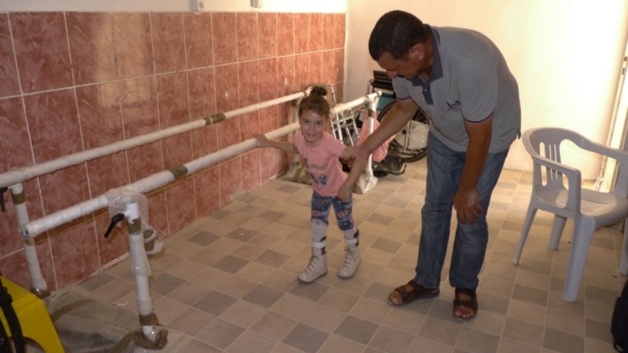 Yasmin au centre de rééducation avec son père, où elle est suivie par Handicap International