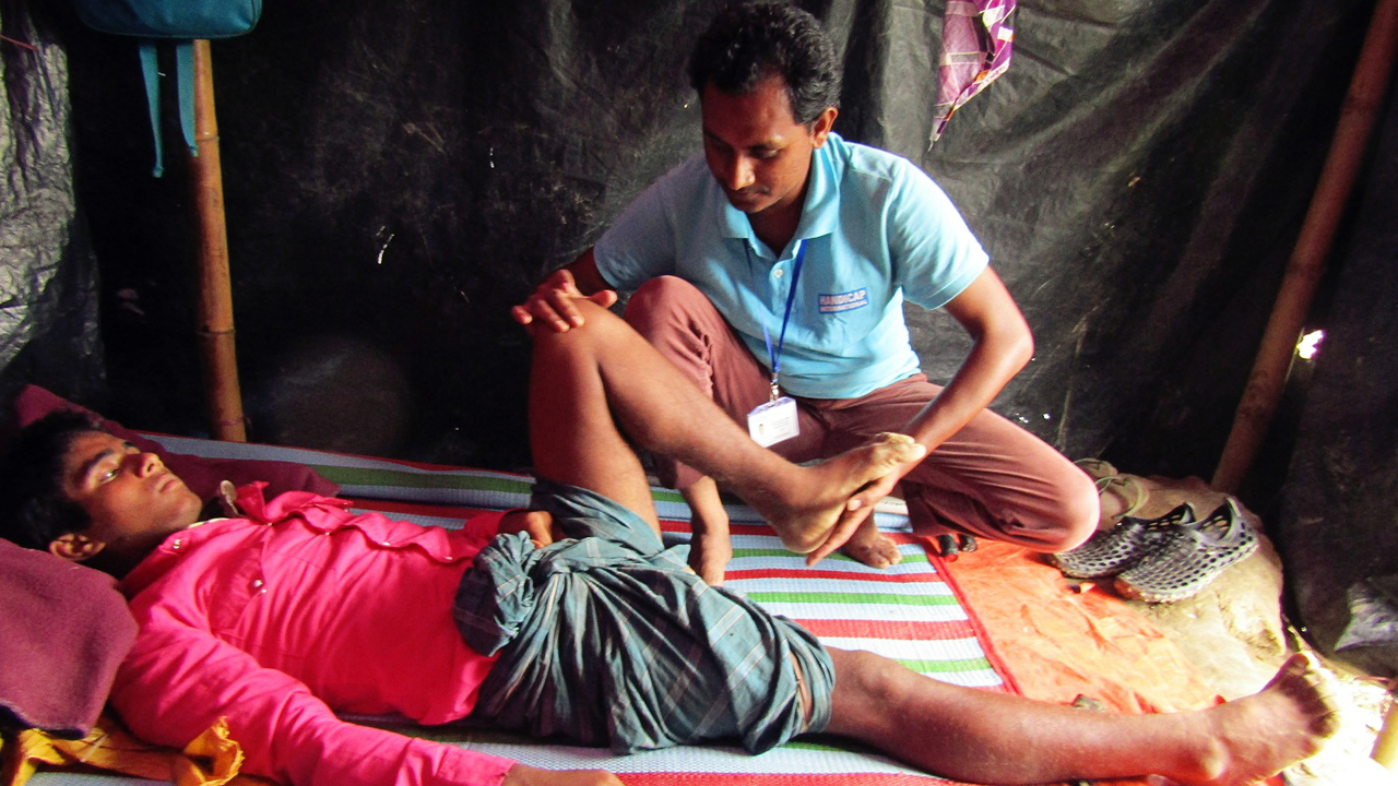 Abu Sadeq avec le kinésithérapeute de Handicap International dans le camp de réfugiés au Bangladesh