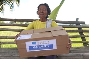 Une femme aveugle porte un carton d'aide alimentaire aux Philippines.